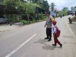 Personel Polsek Kuta Makmur Bantu Seberangkan Anak SD di Persimpangan Krueng Manyang